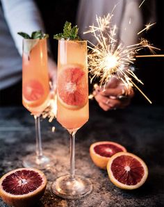 two champagne flutes filled with grapefruit and sparklers