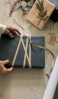 a woman is wrapping up a present on a table with other presents and decorations around her