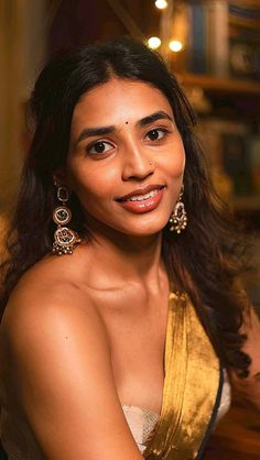 a woman in a gold dress smiling at the camera