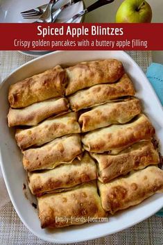 sliced apple blintzes in a white dish on a table with fork and knife