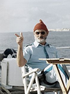 a man sitting in a chair on top of a boat giving the thumbs up sign