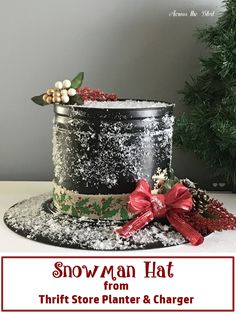 a black and silver cake with red bows on it sitting next to a christmas tree