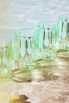 several green glass cups lined up next to each other with lemon slices on the side