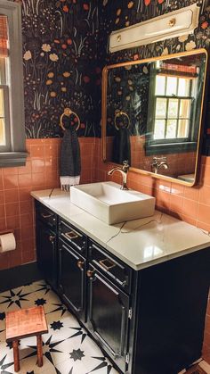 a bathroom with a sink, mirror and tiled flooring in black and white colors