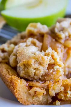 a close up of food on a plate with a fork and an apple in the background