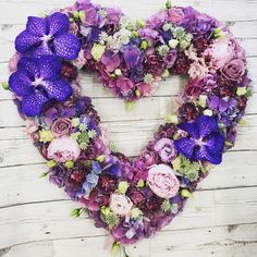 a heart shaped wreath with purple flowers and greenery