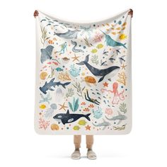 a child is holding up a blanket with sea animals on it and under the water