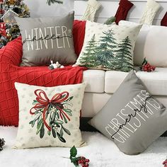 christmas pillows are sitting on the floor in front of a white couch with red and green decorations