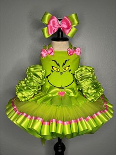 a green dress with pink bows and a grin face on the front, sitting on a mannequin