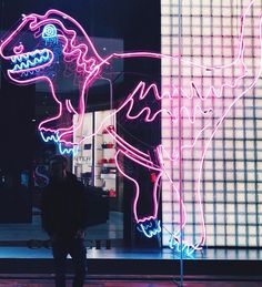 a person standing in front of a building with neon lights on the side of it