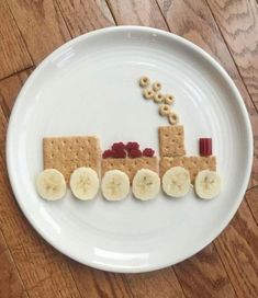 a white plate topped with crackers and bananas on top of a train shaped cutout