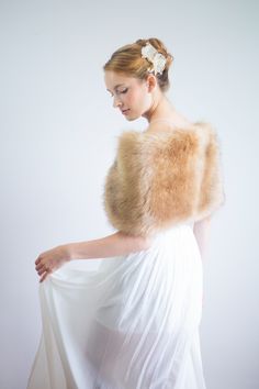 a woman in a white dress with a fur stole around her neck and hands behind her back