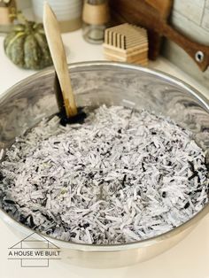 a bowl filled with shredded white rice on top of a counter next to a wooden spatula