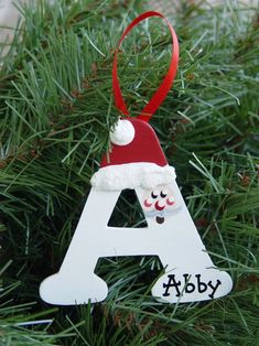 a christmas ornament hanging from a tree with the name aby on it