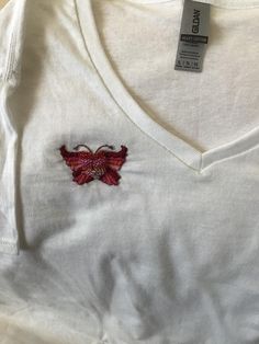 a white shirt with a red butterfly embroidered on it