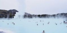 many people are swimming in the blue lagoon with steam rising from it's sides