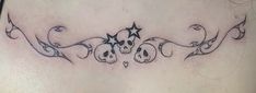 a woman's lower back tattoo with skulls and stars on the side, in black ink