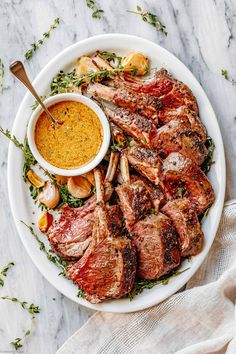 a white plate topped with meat and veggies next to a bowl of mustard