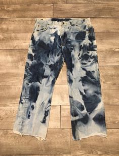 a pair of blue jeans with black and white paint on them sitting on a wooden floor