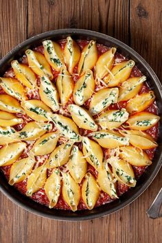 a pan filled with pasta and sauce on top of a wooden table