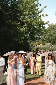 a group of people standing around each other with umbrellas in their hands and onlookers behind them