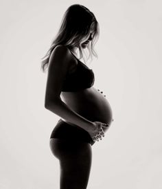 a pregnant woman in a black and white photo holding her belly up to the side