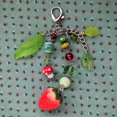 a close up of a key chain with fruit and vegetables attached to it on a fabric background