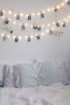 there is a bed with pictures on the wall and lights strung above it that says love