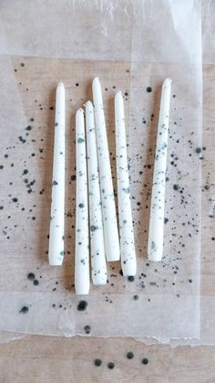 four white candles sitting on top of a piece of wax paper next to black dots