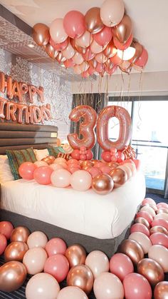 a bed topped with lots of balloons next to a birthday cake and number 30 sign