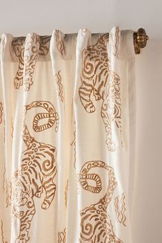 a curtain with an animal pattern hanging on it's rodo - end, in front of a white wall