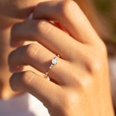 a close up of a person wearing a ring with an opal stone on it