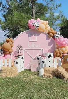 a pink barn decorated with balloons and farm animals