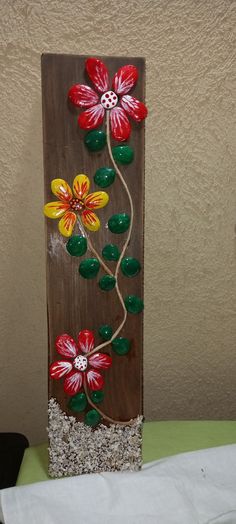 a wooden sign with flowers painted on it's sides and stones in the bottom