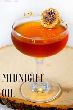 the midnight oil cocktail is served in a coupe glass with an orange garnish