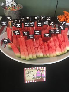 watermelon slices cut up to look like pirate flags and other foods on a table