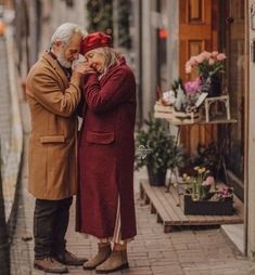 an older couple is standing in the rain outside their house together, looking at each other's eyes