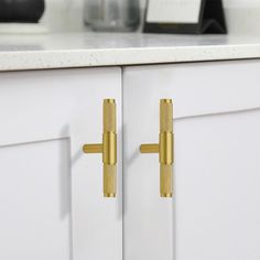 two golden handles on white cabinets in a kitchen