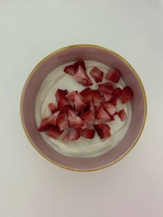 a bowl filled with yogurt and strawberries on top of a white table