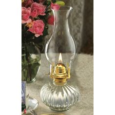 a glass vase with a candle inside on a table next to a plate and flowers