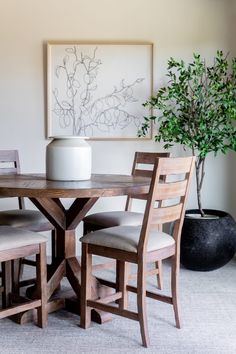 a dining room table with four chairs and a vase