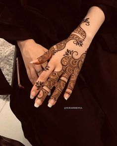 a woman's hand with henna tattoos on it and her hands in the middle