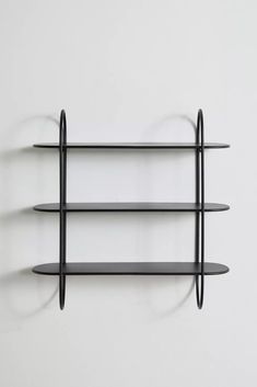 three black shelves on the wall with one shelf hanging from it's side and another shelf below