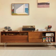 a record player sitting on top of a wooden cabinet next to a wall with pictures above it