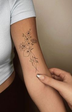 a woman with a tattoo on her arm holding a flower in one hand and an arrow in the other