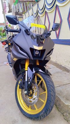 a black and yellow motorcycle parked next to a building