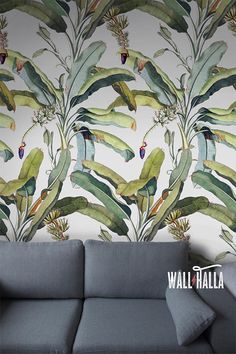 a couch sitting in front of a wallpaper with leaves and flowers on it's side