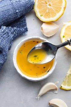 a bowl of soup with lemons, garlic and cloves on the side