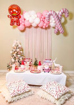 a table topped with lots of pink and white balloons next to a christmas themed wall