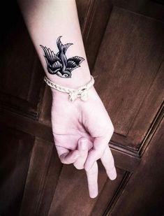 a person's hand with a bird tattoo on their wrist and the other hand is pointing